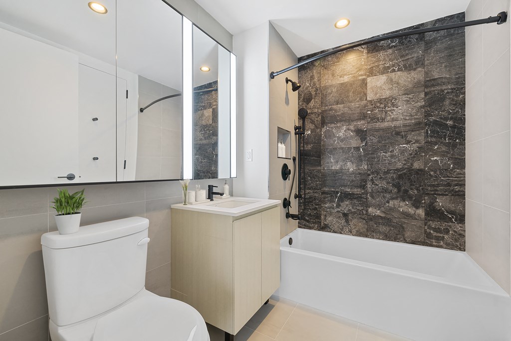 a bathroom with a white toilet and a shower and a sink at The Paxton, Brooklyn